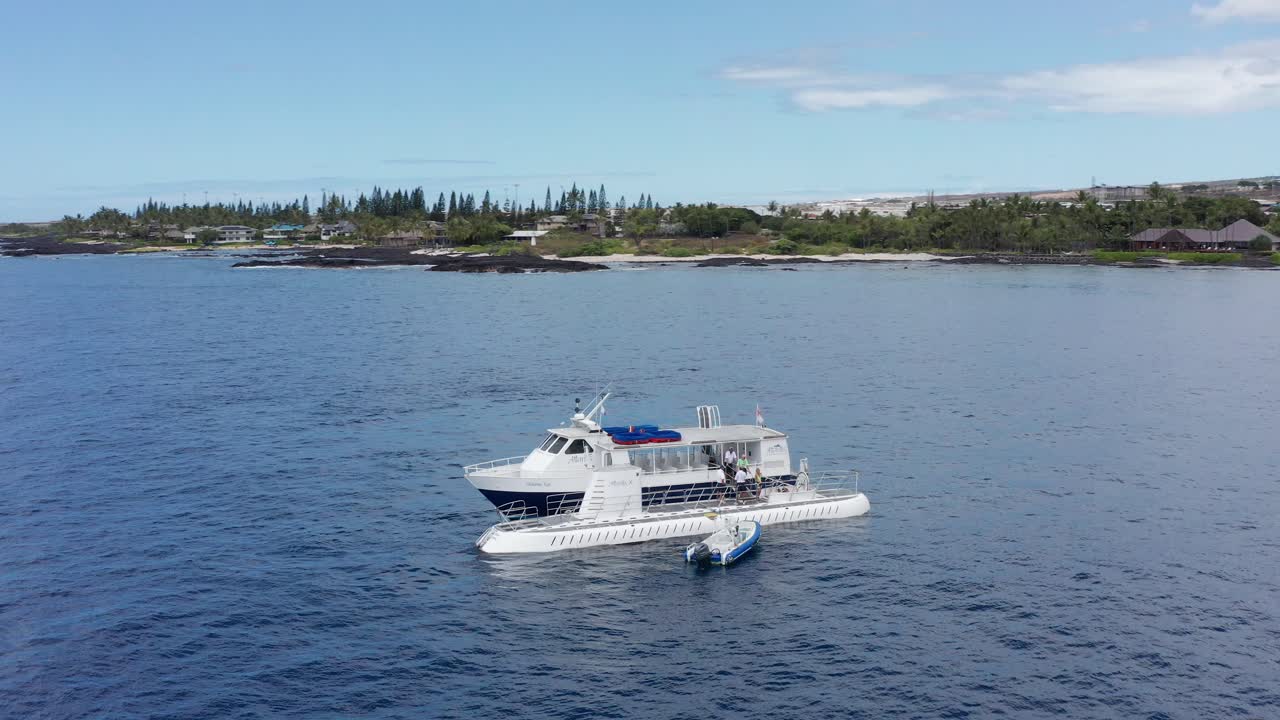 Low panning aerial shot of people boarding a submarine off the shores of Kailua-Kona on the island of Hawai'i