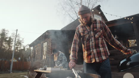 man preparing meat on bbq grill in backyard