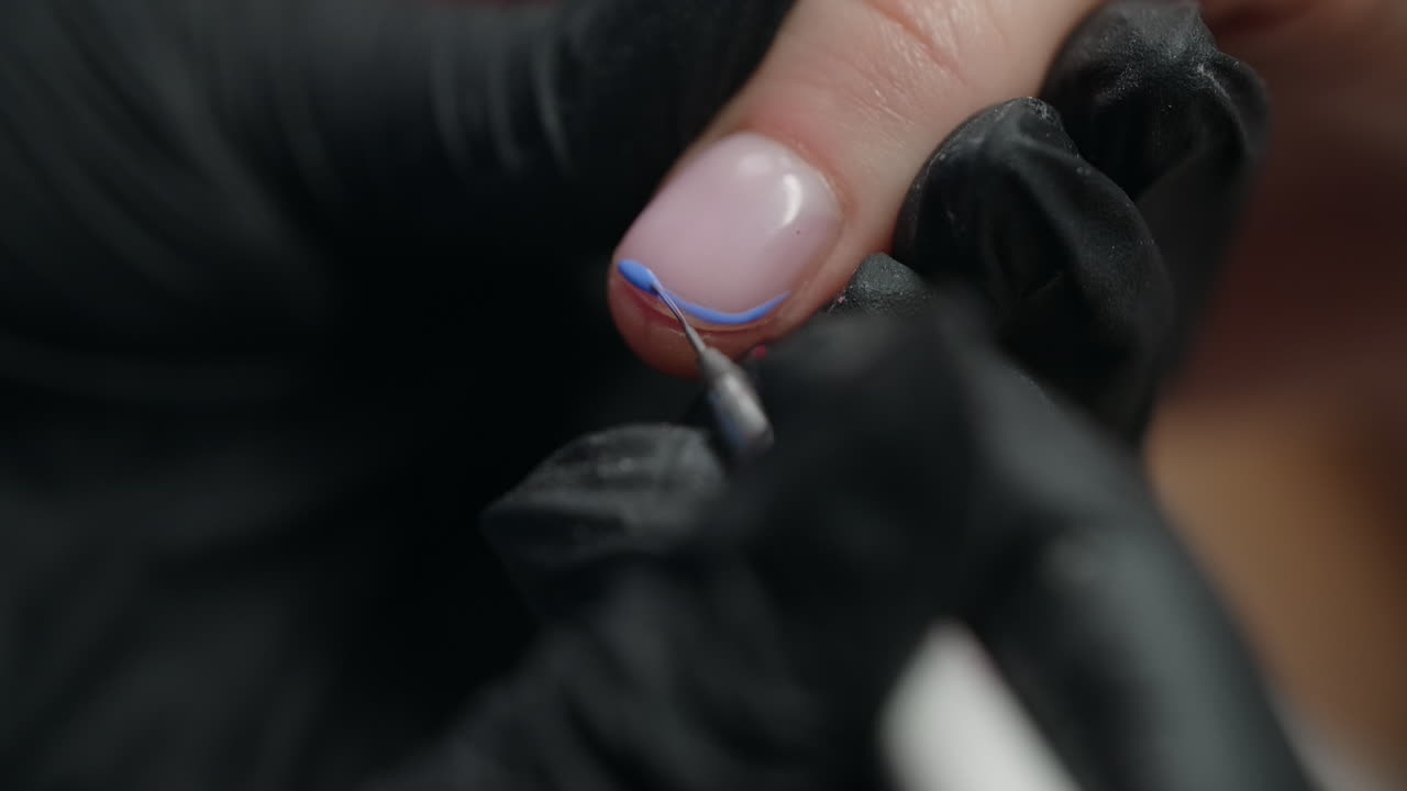 Woman getting her nails decorated with blue design