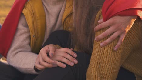 guy and girl join hands sitting at bonfire in camp closeup