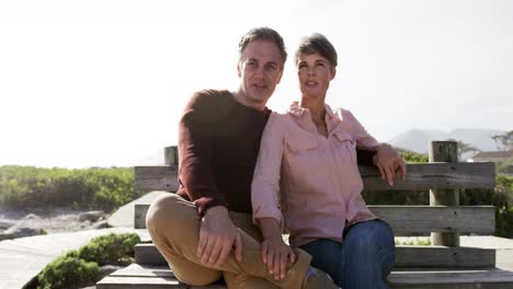 pareja caucásica disfrutando del tiempo libre en el mar en un día soleado sentada en un banco