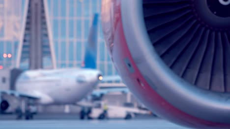 the plane is standing next to the airport building, the red turbine rotates