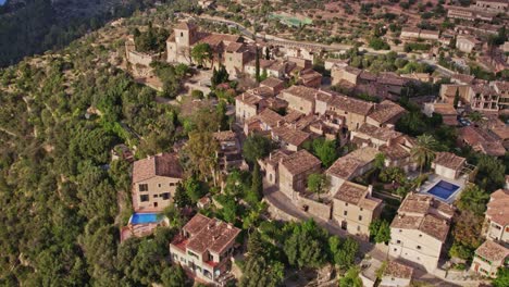 Wide-shot-of-beautiful-mountain-village-Deià-on-Mallorca-during-sunset,-aerial