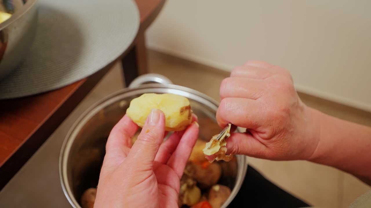 Boiled potato skin removed by woman hand in close-up food preparation moment
