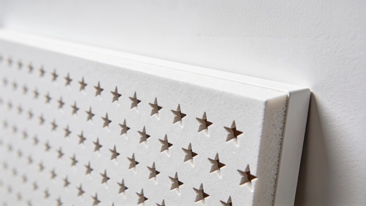 Panning camera revealing thin dark strip at perforated panel right edge with star holes, copy space