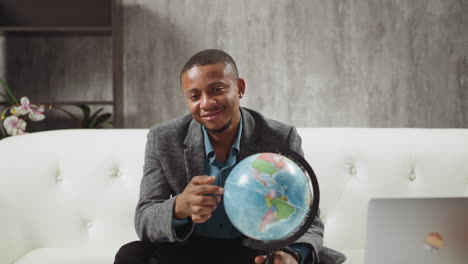 african-american geography teacher finger walks along globe