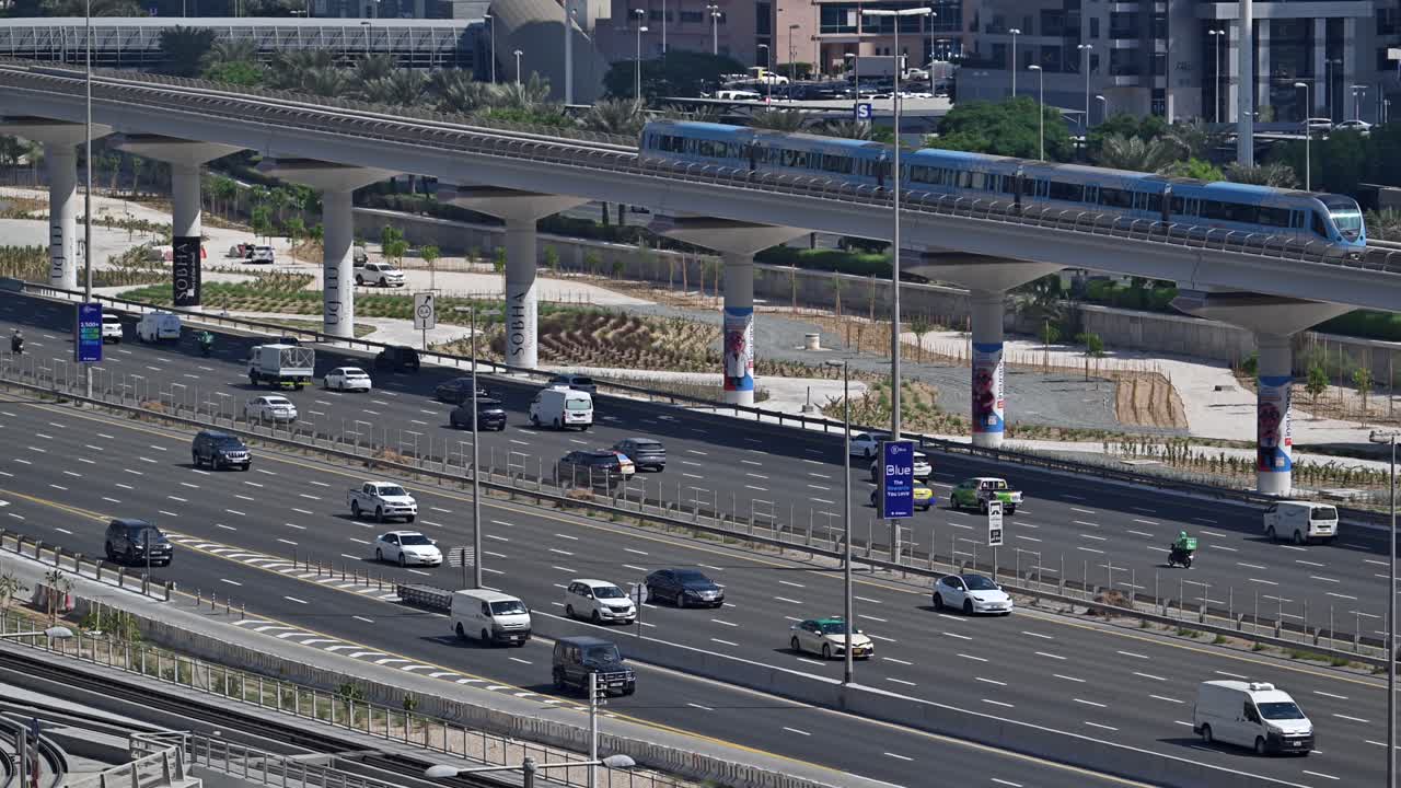 Traffic flows along Dubai’s Sheikh Zayed Road with a Metro train passing through the Marina area, UAE.
