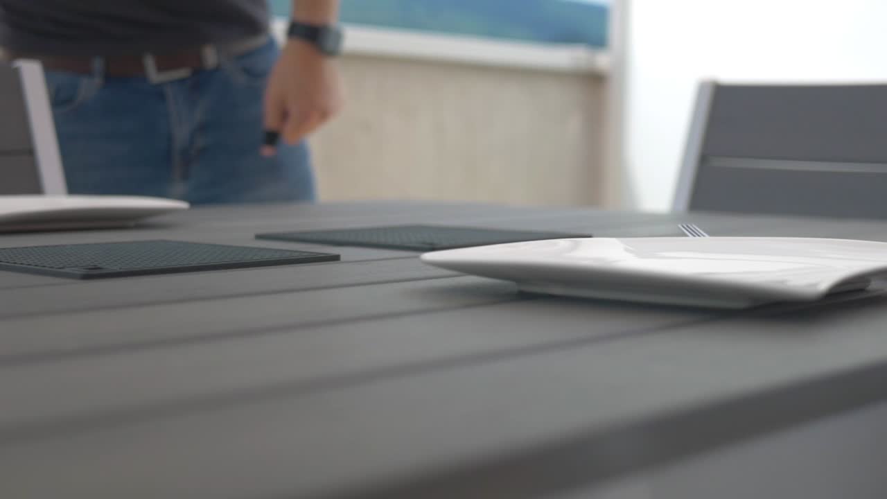 Some puts plates on a table, the camera is on a slider and moves to the left