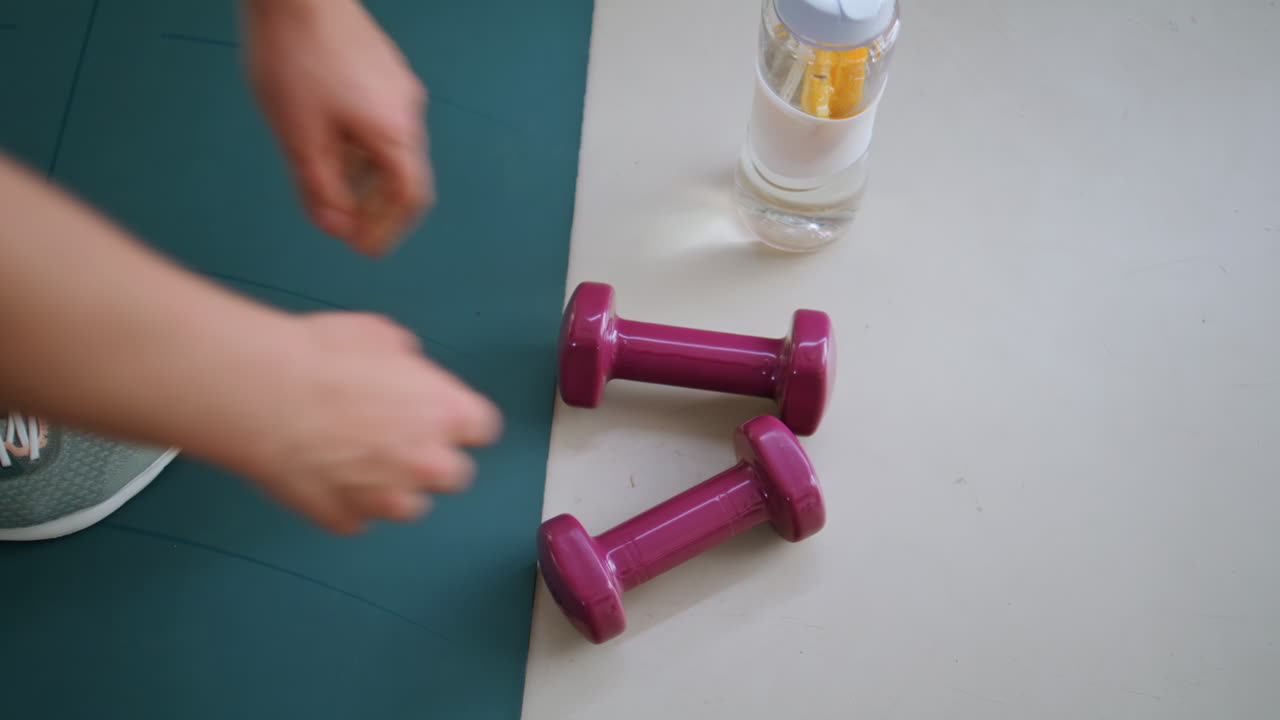 Woman hands placing dumbbells on floor at indoors workout closeup. Wellness