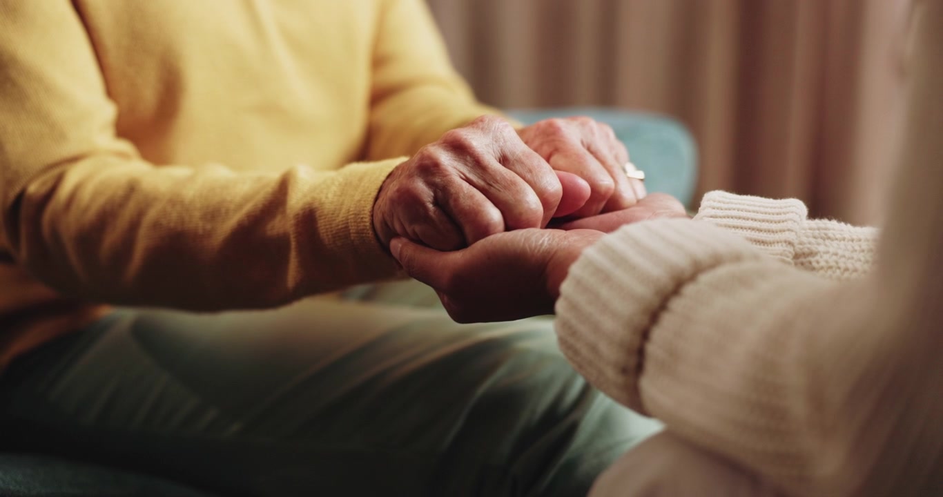 Primer plano de dos personas tomándose de las manos en señal de consuelo y apoyo