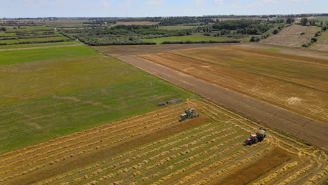 aerial dolly forward over tractors harvesting crops from scenic agricultural farm field