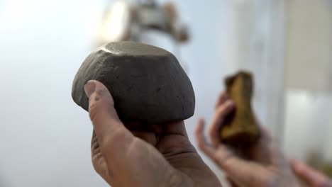 smoothing out a handmade clay bowl with a sponge in a ceramics workshop, handheld close up shot