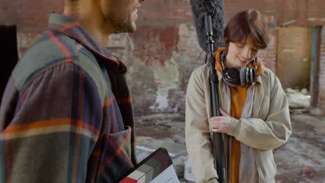 close up view of two coworkers holding material for a recording while talking in a ruined building