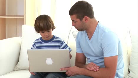 Concentrated-father-explaining-his-son-how-to-use-a-laptop