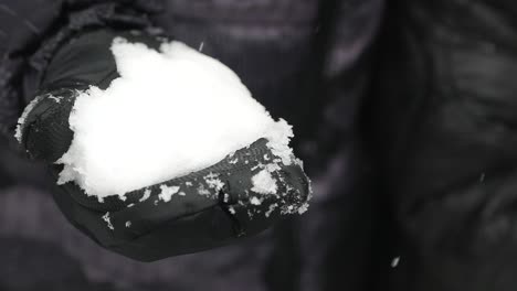 hand holding a snowball in winter gloves