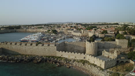 Una-Vista-Aérea-De-La-Ciudad-De-La-Isla-De-Rodas-En-Grecia-Que-Contiene-Clips-Del-Casco-Antiguo-Medieval,-El-Antiguo-Faro-Del-Puerto,-Antiguos-Molinos-De-Viento,-Playas-Y-Una-Increíble-Puesta-De-Sol