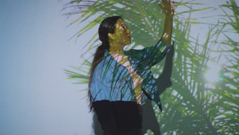 woman visiting and interacting with immersive art exhibition with images of palm leaves being projected onto her face