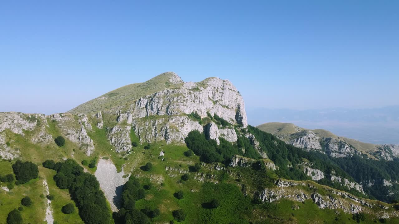 aérea que se acerca a un hermoso pico de montaña con un acantilado empinado y el borde del bosque