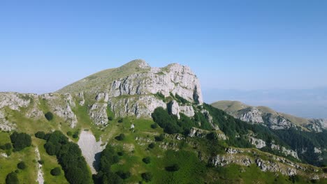 aerial approaching beautiful mountain peak with steep cliff and the edge of the forest