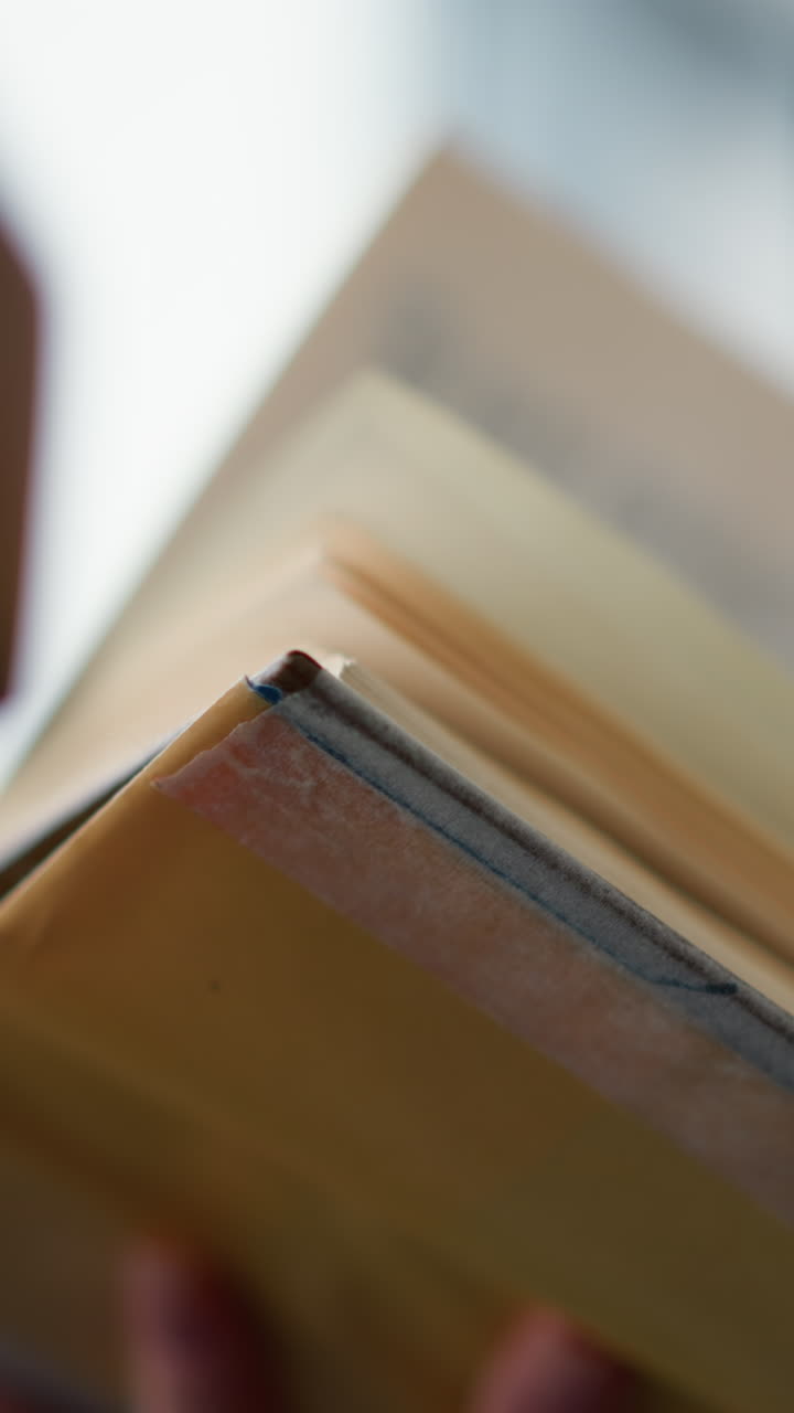 Close-up of lady in woven clothing attempting to flip to the next page of a book with a slight blur of the background, the soft texture of her sweater contrasts with the clarity of the book