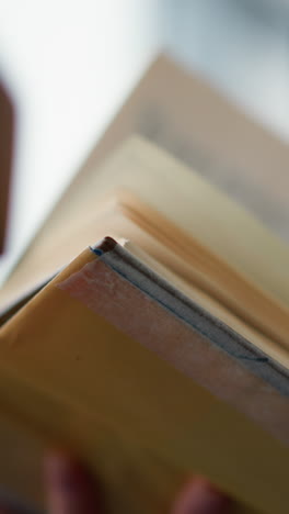 primer plano de una mujer con ropa tejida intentando pasar a la siguiente página de un libro con un ligero borrón del fondo, la textura suave de su suéter contrasta con la claridad del libro