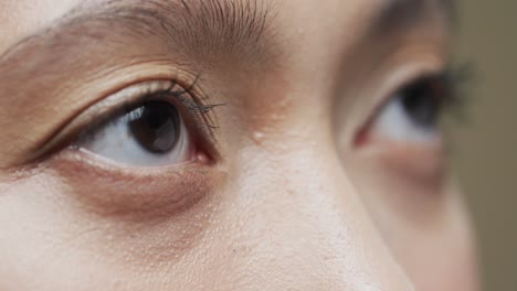 eyes of asian woman with dark hair on beige background, slow motion