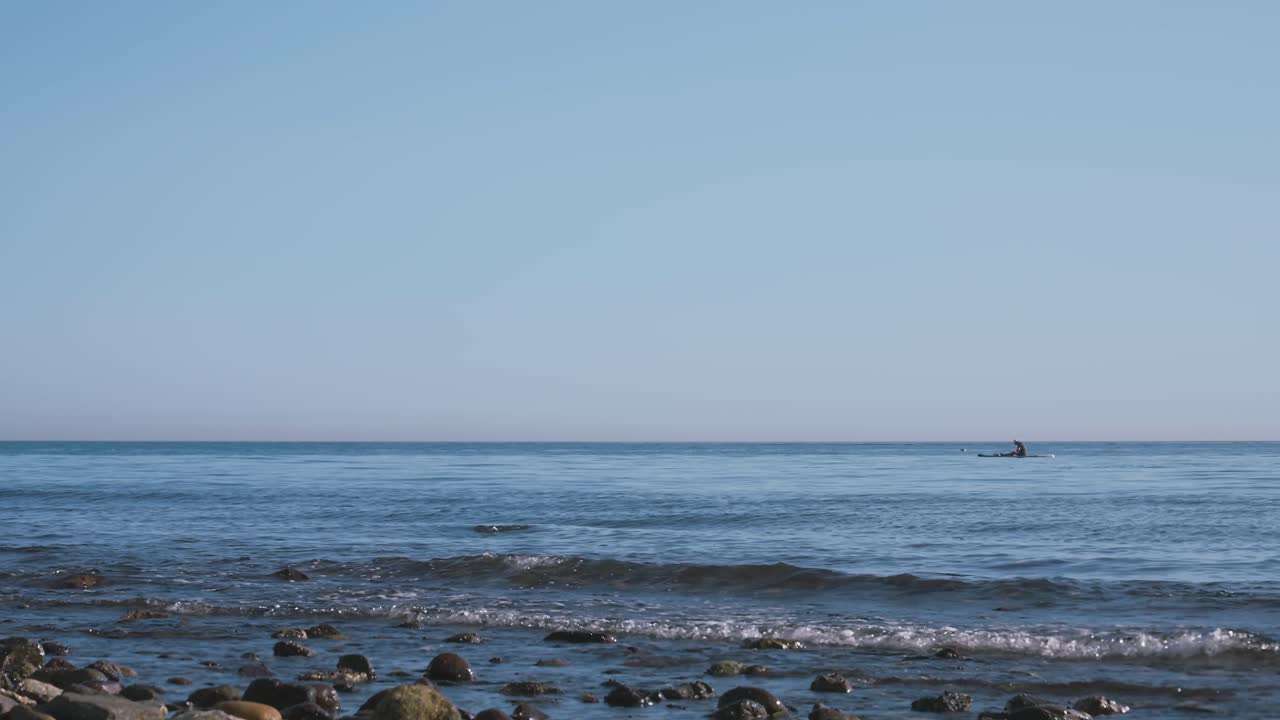 120fps는 거리에서 패들링 보드에 남자와 함께 해변의 영상을 가속화했습니다.
