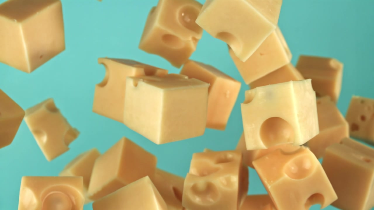 Cubetti di formaggio che cadono al rallentatore su sfondo blu