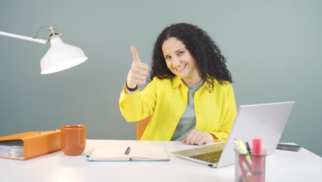 mujer joven mirando la computadora portátil haciendo un gesto positivo.