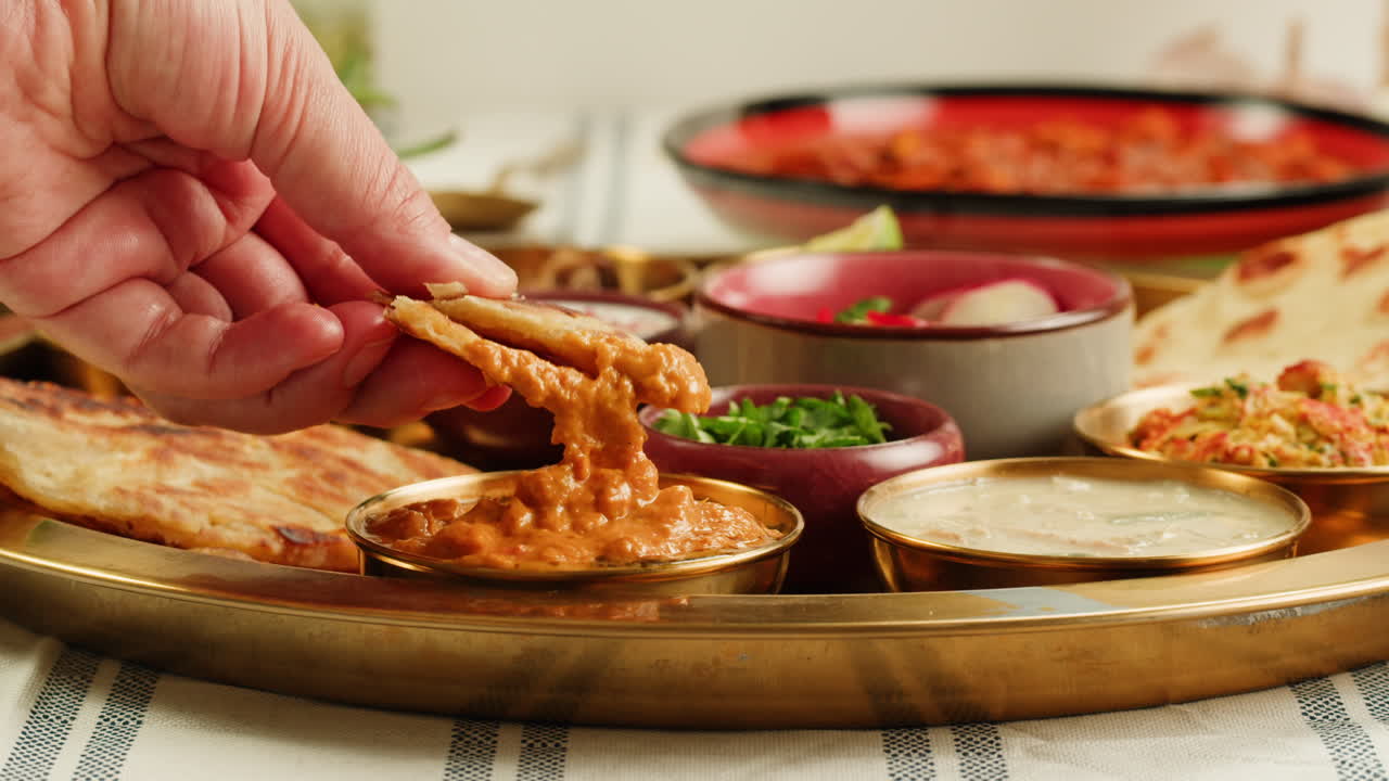 Assorted indian sri-lanka food set on wooden background. Dishes and appetisers of indeed cuisine, rice, lentils, paneer, samosa, spices, masala. Bowls and plates with indian food top view chicken. High quality 4k footage