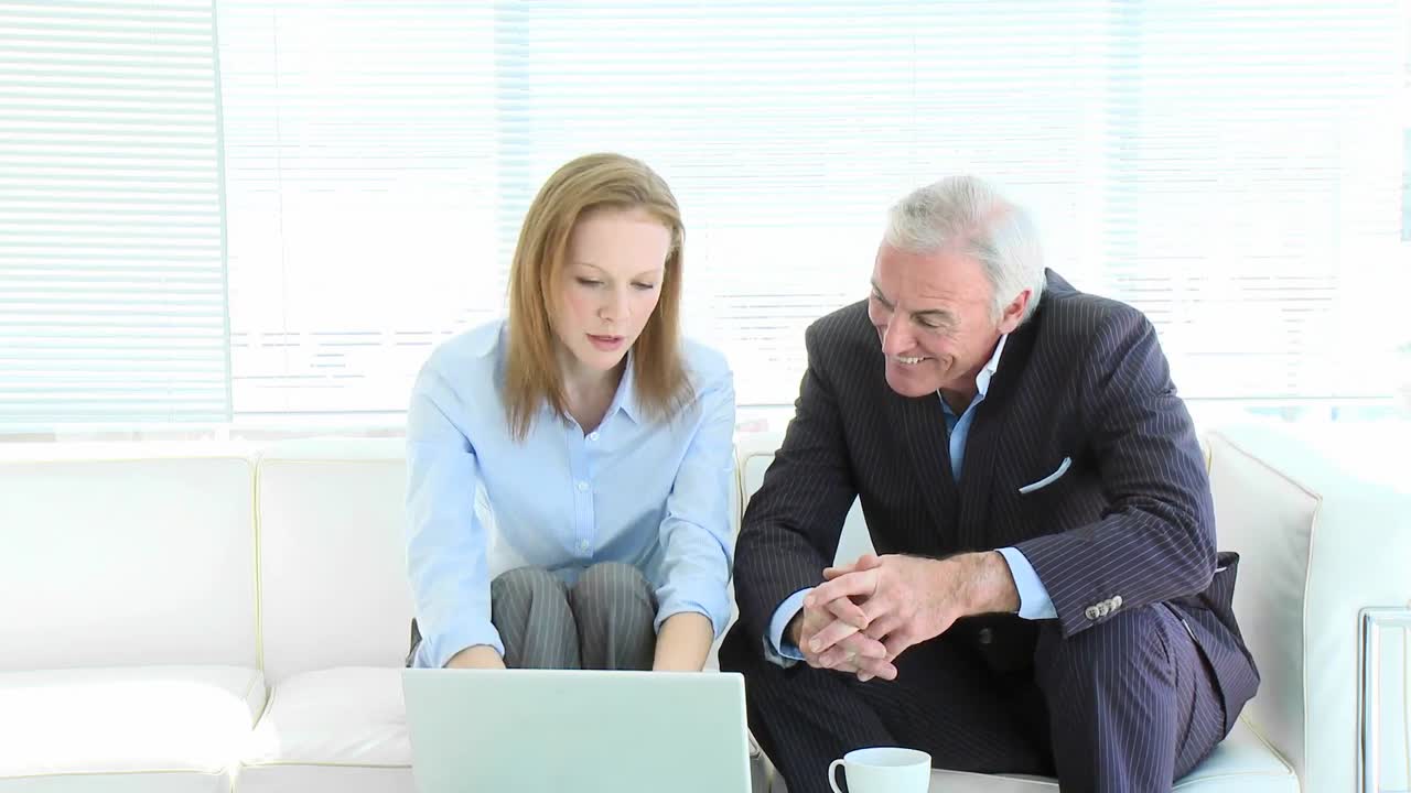 Donna d'affari e uomo d'affari maturo che lavorano con un computer portatile