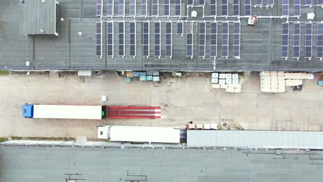 Trucks-with-semi-trailers-stand-on-the-parking-lot-of-the-logistics-park-with-loading-hub-and-wait-for-load-and-unload-goods-at-warehouse-ramps-at-sunset