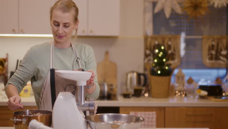 smiling woman works in the kitchen using a meat grinder preparing a holiday pate