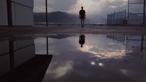 reflejo de un joven en el charco, mientras caminaba y apreciaba los cielos que brillaban a través de las montañas - ángulo bajo