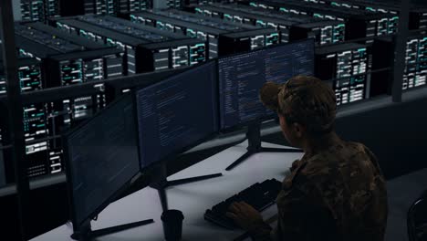 side view of tired asian military stretching while write code with multiple computer screens in data center