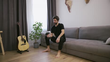 hombre haciendo ejercicios con pesas en casa en la sala de estar en el sofá