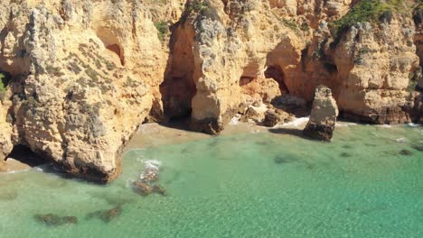 Hidden-beach-hideaways-among-the-rugged-cliffs-of-Algarve-coastline,-Portugal---Aerial-Panoramic-orbit-shot