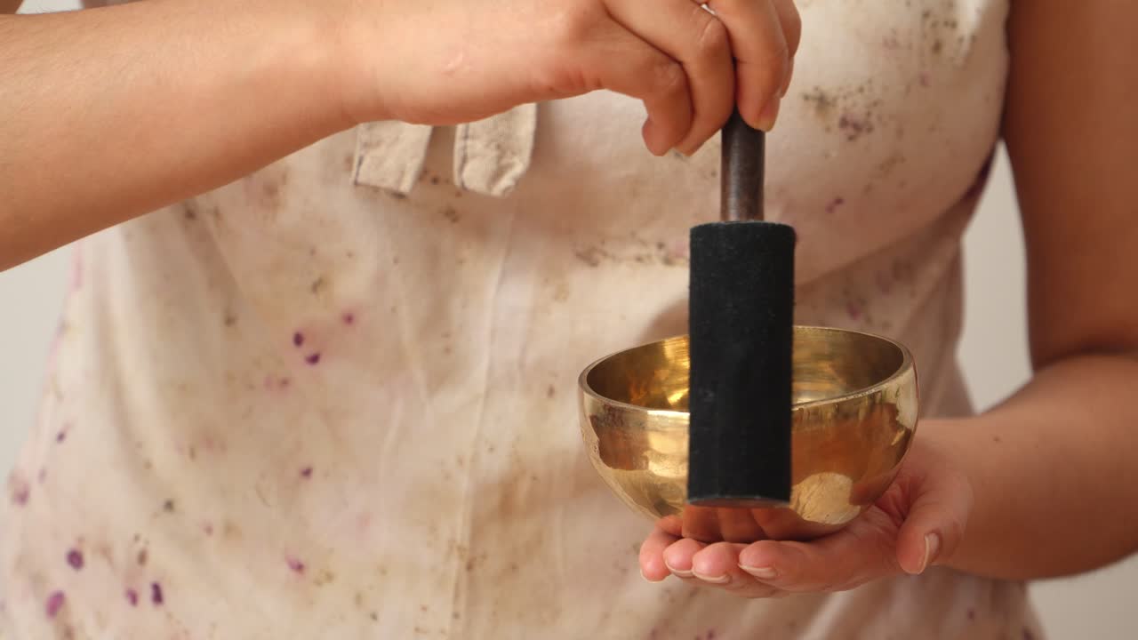 Hands producing resonance in small Tibetan singing bowl with traditional method