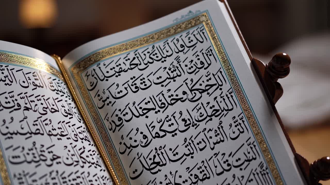 Close-up video of an open Quran on a wooden stand, showcasing intricate Arabic calligraphy