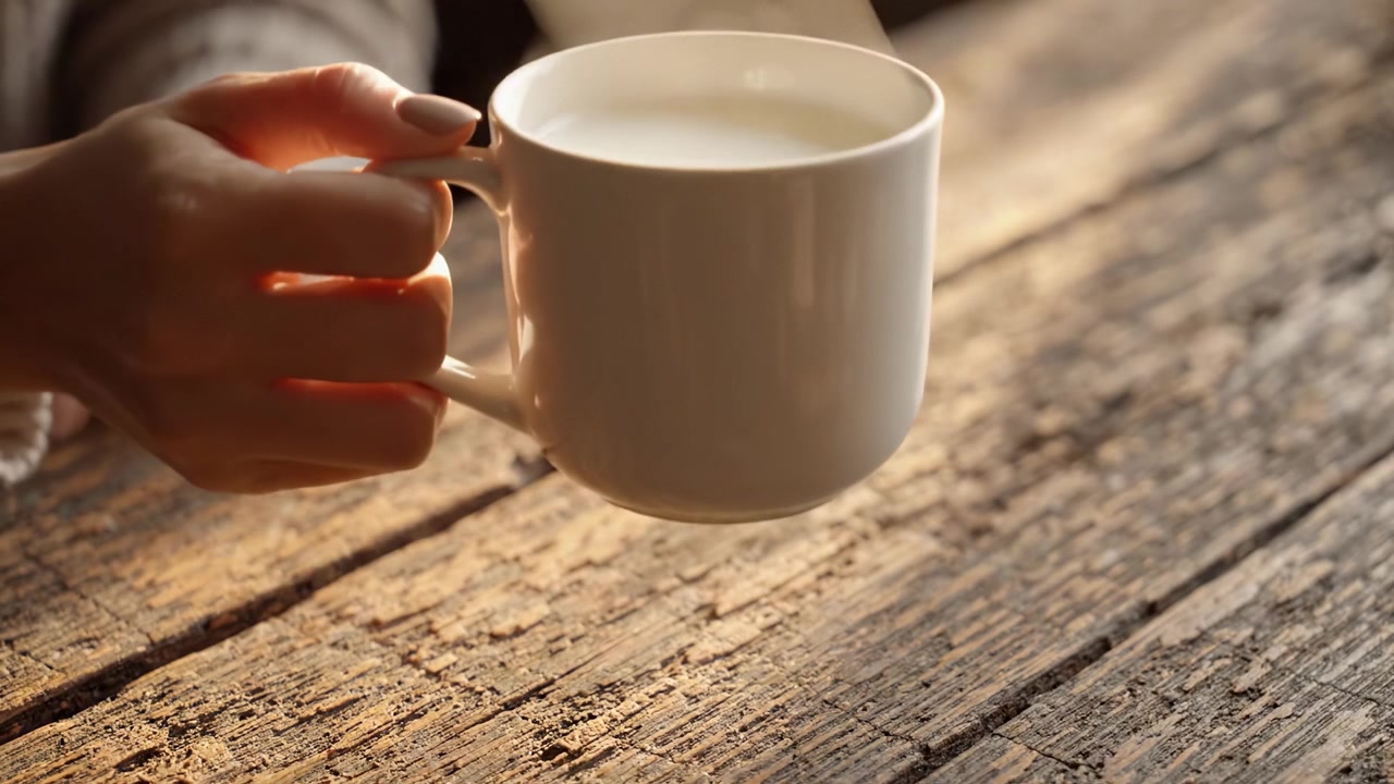 Un momento accogliente: gustando una tazza di latte caldo su un tavolo di legno rustico, catturando l'essenza del comfort e della tranquillità nella vita quotidiana