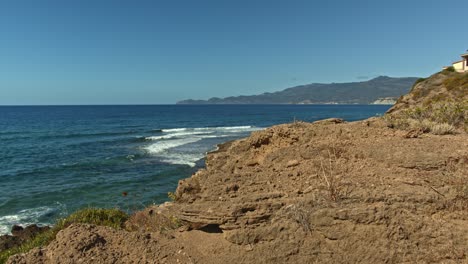 rocky ocean coastline cliff with small house on top, motion shot