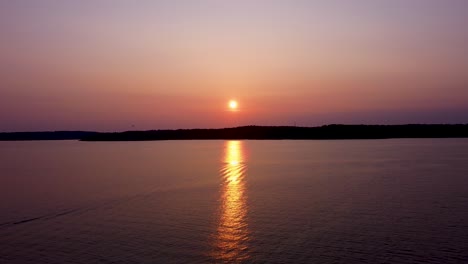 yellow sunset reflects on calm sea water in stockholm archipelago, aerial view