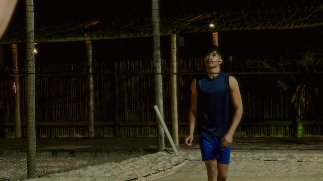 Men playing beach volleyball at night