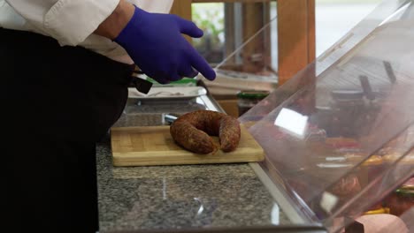 Vista-De-Las-Manos-De-Un-Chef-Cortando-Y-Sirviendo-Carne-Salada-Con-Carne-Molida-En-Palillos-De-Dientes-En-La-Cocina-De-Un-Hotel