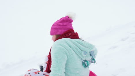 Disparo-A-Cámara-Lenta-De-Una-Niña-Bajando-En-Trineo-Una-Colina-En-Invierno