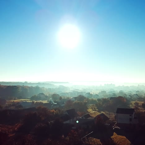 aerial top view of the small houses at sunrise. rural landscape of house roofs, roads and tree tops in spring or summer day. camera moves forward.