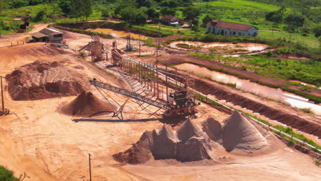 drone aerial pan of sand dredger machinery tools for extraction removing sediment operations sand piles industry in countryside farmland property dam brazil south america.