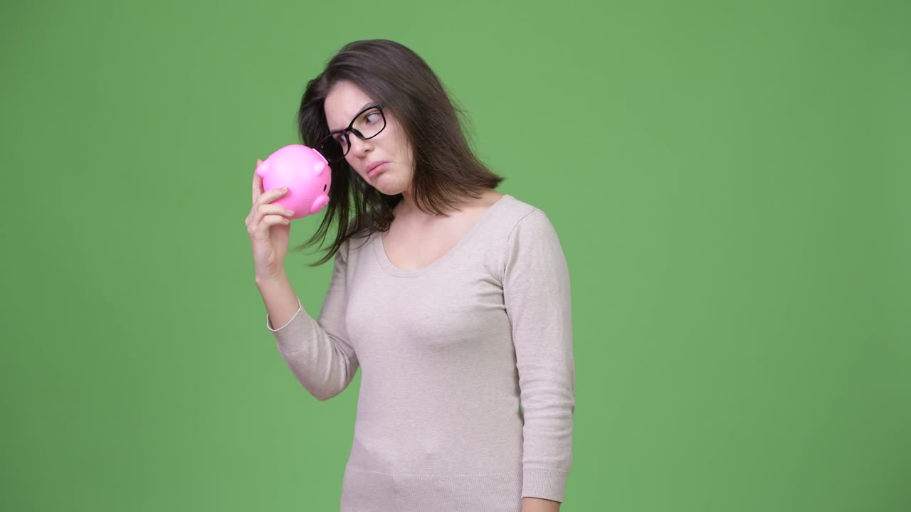 una joven hermosa sacudiendo la alcancía.