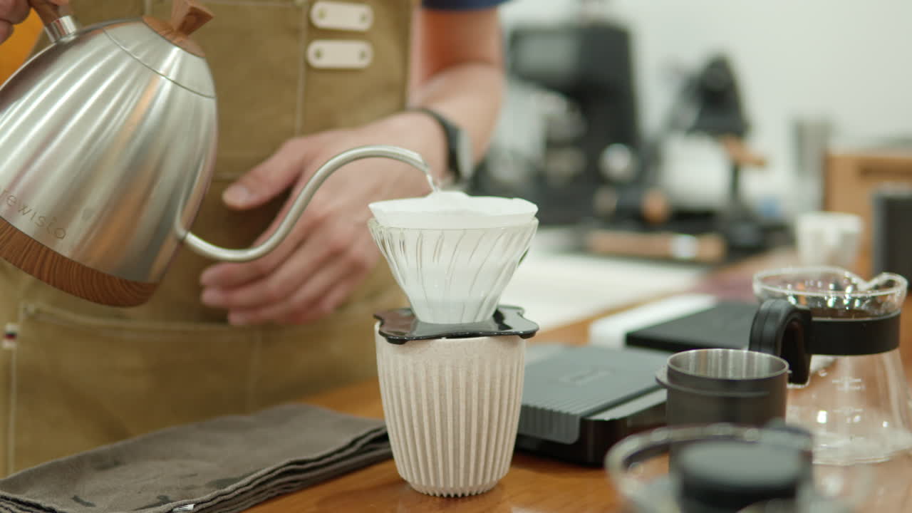 바리스타 남자가 종이 필터 드립을 사용하여 커피를 조리하고 있습니다.