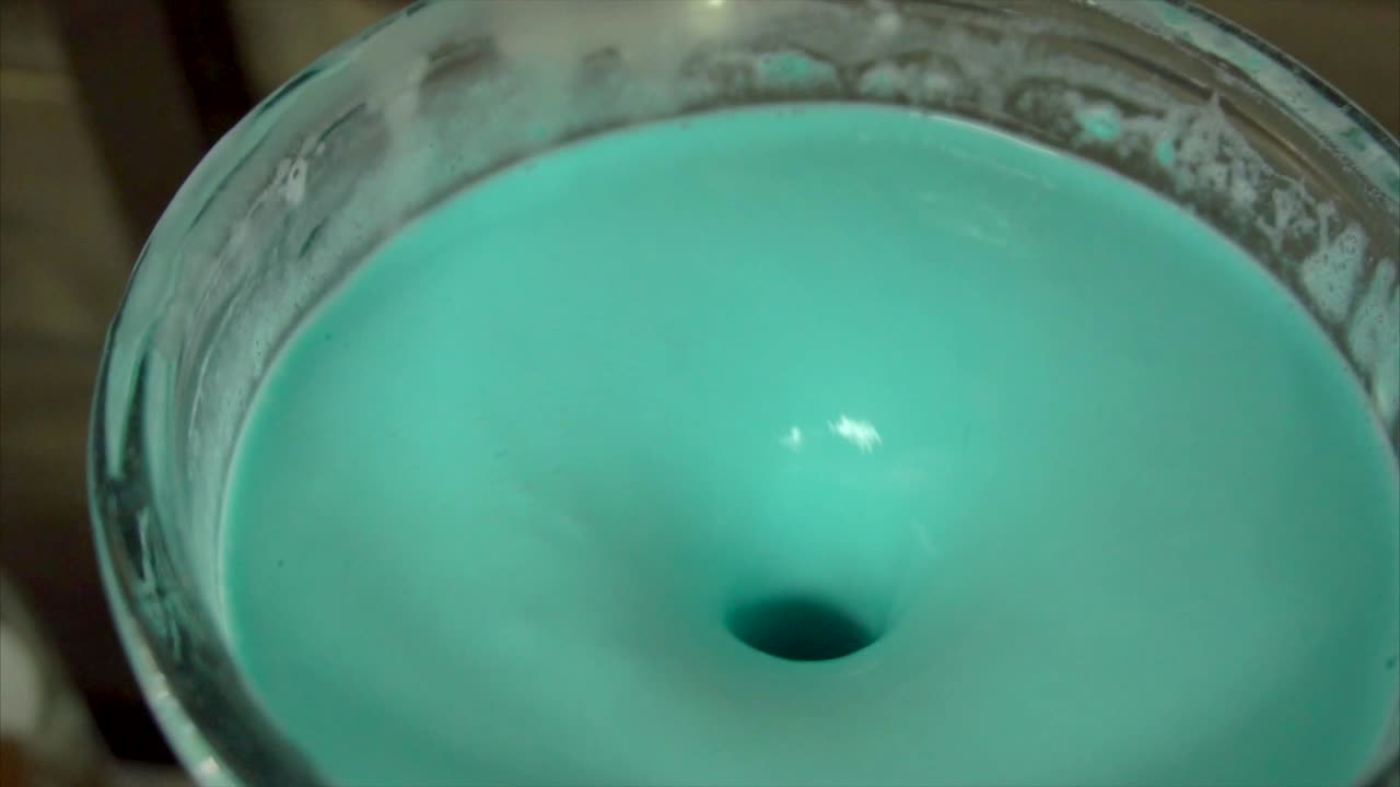 vórtice líquido azulado en un recipiente de vidrio